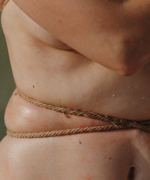 Crop shot of unrecognizable female's body corded with rope. Conceptual shot about self rejection, imperfection and pain